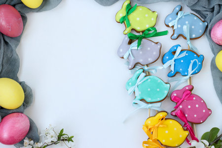 Easter gingerbread in the form of cute rabbits on sticks located on a white background, top view,...