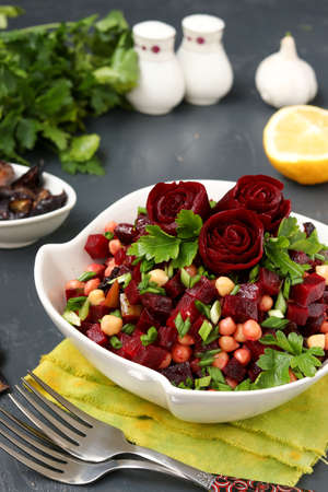 Lean chickpea and beetroot salad decorated with beetroot roses in a white salad bowl on a dark backgroundの写真素材