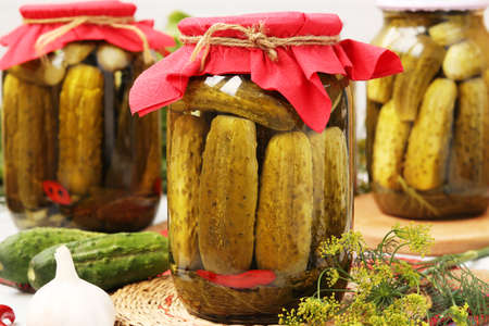 Marinated cucumbers in jars, garlic and dill on a white background, harvest for the winterの写真素材