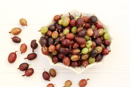 Gooseberry berries are located in a plate on a white backgroundの写真素材