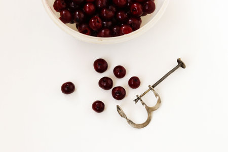 A pitted cherry is located in a bowl on a white background, Removal of bones from cherries by special adaptationの写真素材