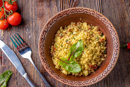 Couscous in bowl with olive oil and dried tomatoes on wooden background, oriental cuisine, horizontal photo, close upの写真素材