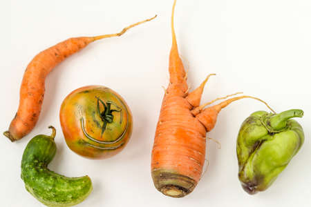 Five ugly vegetables: carrots, cucumber, peppers and tomatoes on white background, ugly food concept, horizontal photo, top viewの写真素材