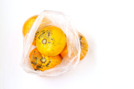 Ulgly organic yellow tomatoes in plastic bag on a white background, Image shows the harm of using...