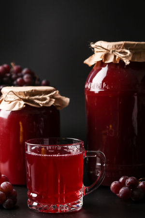 Grape juice in a glass and a cans, cooked in a juicer, harvesting juice from a grape harvest localed...