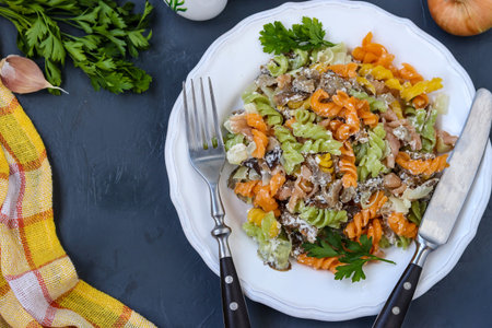Fusilli multicolored pasta with vegetables in a white plate on dark background, top view, horizontal orientation, closeupの写真素材