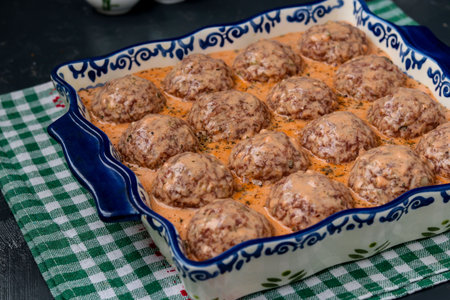 Process of cooking meatballs with rice, which are prepared in ceramic form and poured with sauce,...
