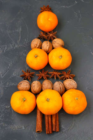 Tangerines, nuts and anise in the shape of a Christmas tree on the dark backgroundの写真素材