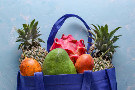 Zero waste concept, Blue shopping textile bag with fresh tropical fruits: mango, pineapple, dragon and passion fruit, horizontal orientationの写真素材