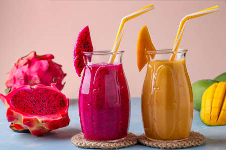 Homemade tropical fruit smoothies made of dragon and mango on a pink background, horizontal orientationの写真素材
