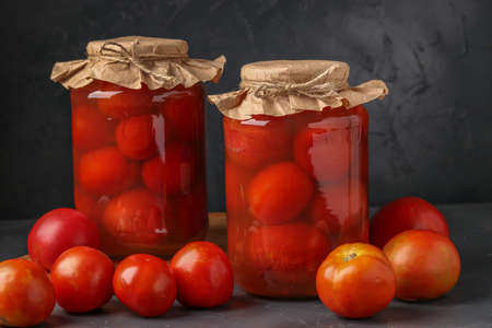 Homemade salted tomatoes in jars on a dark background, Fermented food, closeup, copy spaceの写真素材