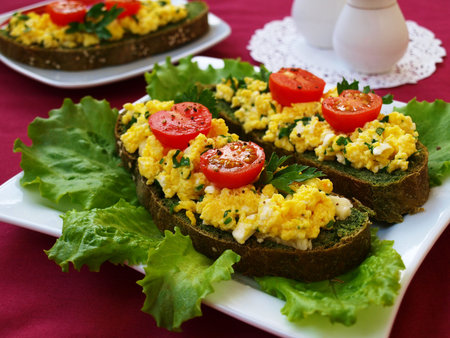 Sandwiches with scrambled eggs and cherry tomatoes on homemade bread with nettles, closeup