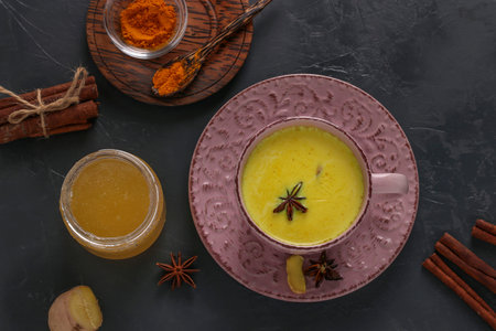 Cup of ayurvedic golden turmeric latte milk with curcuma powder, cinnamon, ginger and anise star on...