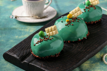 Homemade bright mousse cakes Hearts with green mirror icing on a white background, Closeup,...