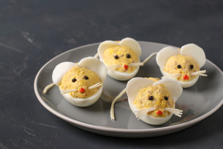Festive snack Mice for 2020 made of stuffed eggs with cod liver on a dark background, Symbolic food...