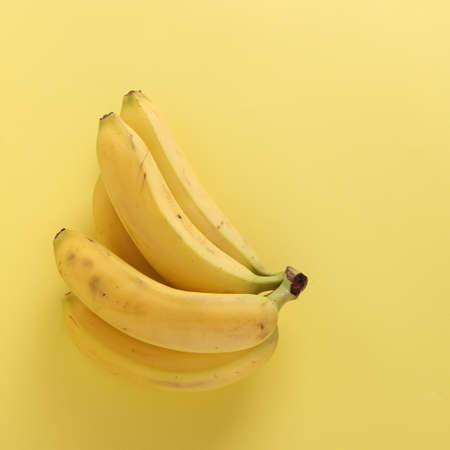 Sweet bananas on punchy pastel yellow background, Top view, Closeupの写真素材