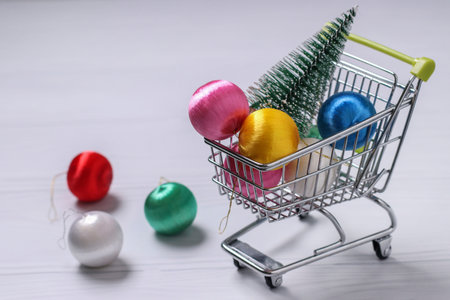 Trolley cart and colorful new year balls on white background, Christmas tree, flat lay shopping, horizontal orientation, Copy space