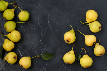 Ripe organic pears are located on dark background in an arbitrary order, Top view, Copy space
