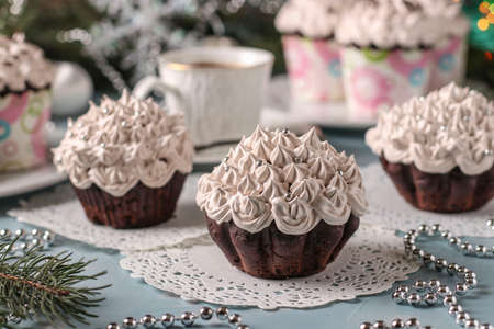 Homemade chocolate cupcakes with cream and a cup of coffee arranged on a light blue background, Closeup, horizontal orientationの写真素材