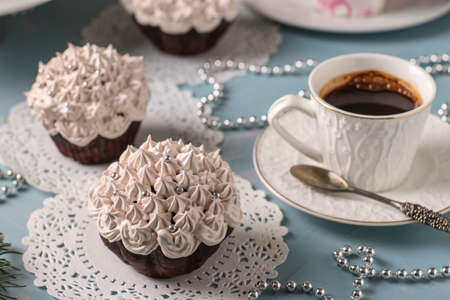 Homemade chocolate cupcakes with cream and a cup of coffee arranged on a light blue background, Closeup, horizontal orientationの写真素材