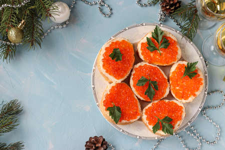Sandwiches with red caviar are located on a plate against a light blue background, Festive snack, Copy space, horizontal orientation, Top viewの写真素材