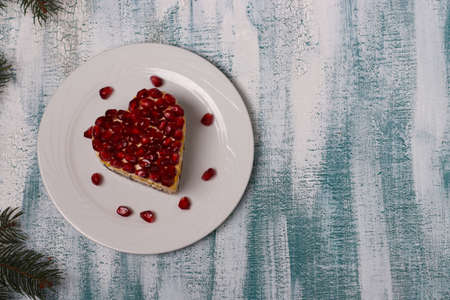 Festive salad in the shape of a heart, decorated with pomegranate seeds on a blue background for Valentine's Day, Horizontal orientation, Copy spaceの写真素材