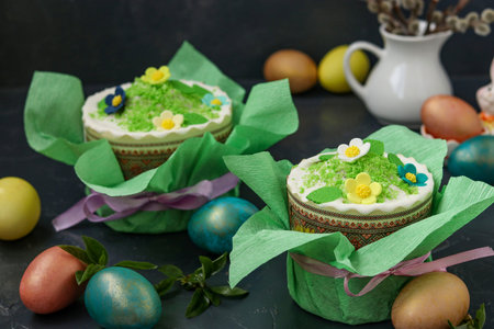 Still life with Easter cakes in gift paper and multi-colored Easter eggs on a dark background,...