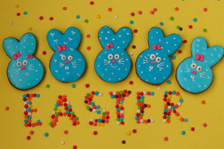Easter funny blue rabbits, homemade painted gingerbread biscuits in glaze on a yellow background