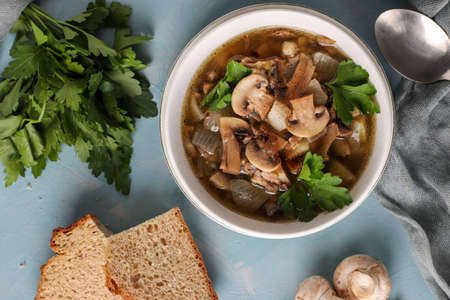 Mushroom soup of champignons and lentils in a white plate on a light blue background, Top view, Closeupの写真素材