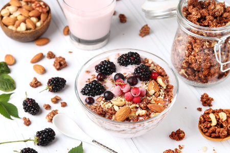 Granola crispy honey muesli with natural yogurt, fresh berries, chocolate and nuts in a bowl against a white background, Healthy food, Closeupの写真素材