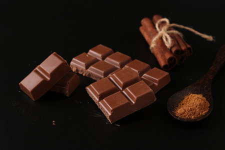 Chocolate with cinnamon on a dark background, with cinnamon sticks in the background, Closeup