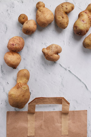 Organic ugly potatoes in a paper bag on a marble background, organic vegetables concept, Zero waste...