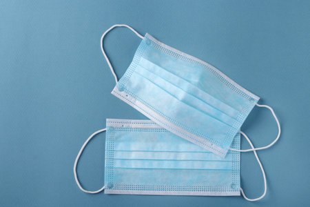 Two protective blue medical face masks on blue background, Prevention of virus