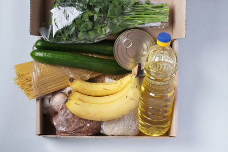 Box with food supplies crisis food stock for quarantine isolation period on light blue. Rice,...