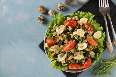 Organic salad with chicken, cherry tomatoes, quail eggs, black olives and microgreens against on light blue background, Healthy Eating Day, Top view, Space for textの写真素材