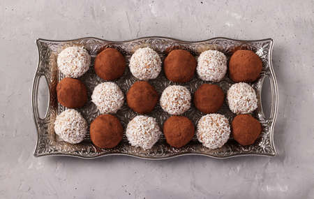Energy balls of nuts and oatmeal with coconut and cocoa on a metal tray on a gray concrete background, horizontal format, Top viewの写真素材