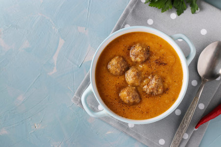 Pumpkin cream soup with meatballs in bowl on light blue background, Horizontal format, Space for...