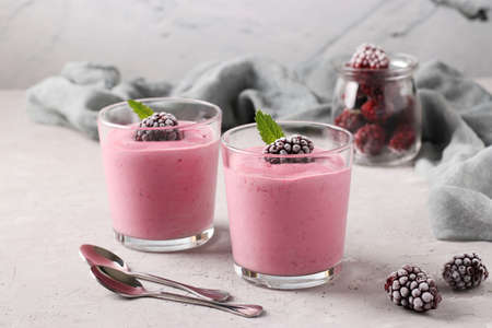 Two servings of homemade smoothies with frozen blackberries in glasses on gray concrete background, Diet and weight loss control conceptの写真素材