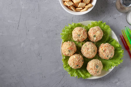 Snack balls with chicken, carrots, cheese and green onions in cracker crumbs, top view on gray...