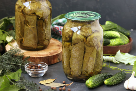 Canned cucumbers in grape leaves in jars on a dark background, Harvest for the winter