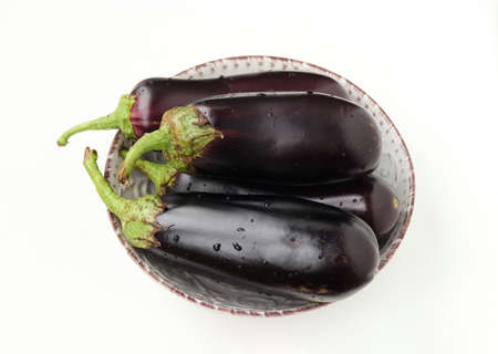 Four large eggplants with drops of water on a plate, white background, organic food concept, Closeupの写真素材