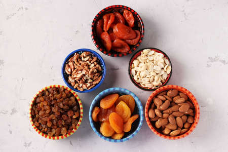 Dried apricot, raisins, peanuts, almonds, walnut in bowls on gray concrete background, Top viewの写真素材