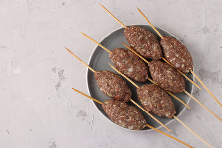 Kofta shashlik on wooden skewers on a plate, preparation process, Top view
