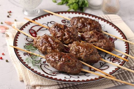 Kofta kebab on wooden skewers on a plate and sauce on the table, traditional dish of Arab cuisine,...