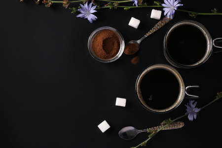 Chicory beverage in two glass cups, with concentrate and flowers on black background. Healthy herbal beverage, coffee substitute, Top view, Space for textの写真素材