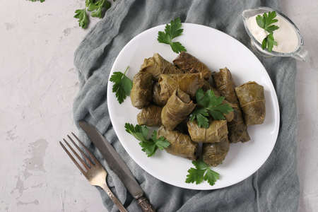 Dolma - stuffed grape leaves with rice and meat on a white plate on light gray background. Traditional Caucasian, Greek, Ottoman and Turkish cuisine, Top viewの写真素材