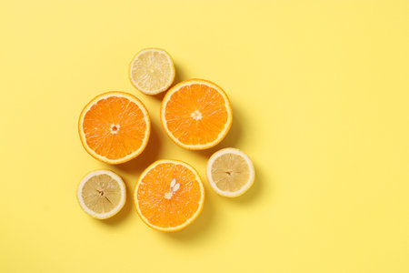 Composition in the style of minimalism of halves lemons and oranges on yellow background with space...