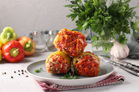 Bell Pepper Stuffed with rice and minced beef in tomato sauce in a plate on light gray background