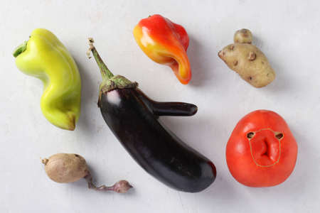 Trendy Ugly Organic Vegetables: potatoes, peppers, eggplant and tomato on gray background, ugly food concept, horizontal format, top viewの写真素材