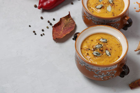 Vegetarian autumn creamy pumpkin soup with red lentils on gray background, copy space, close up